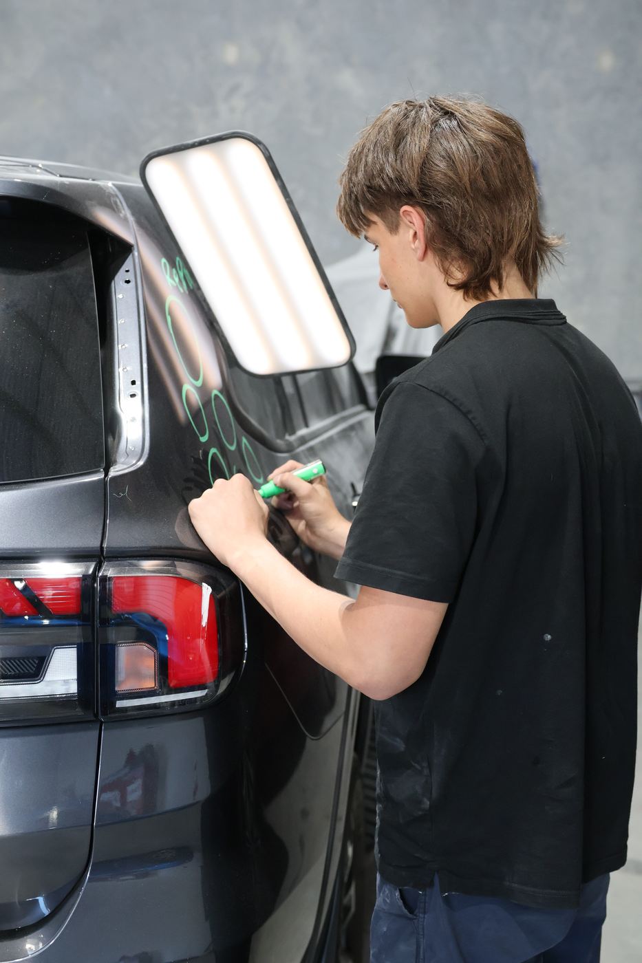 Close-up of dent assessment markings on a dark panel at MRP Automotive Refinishing